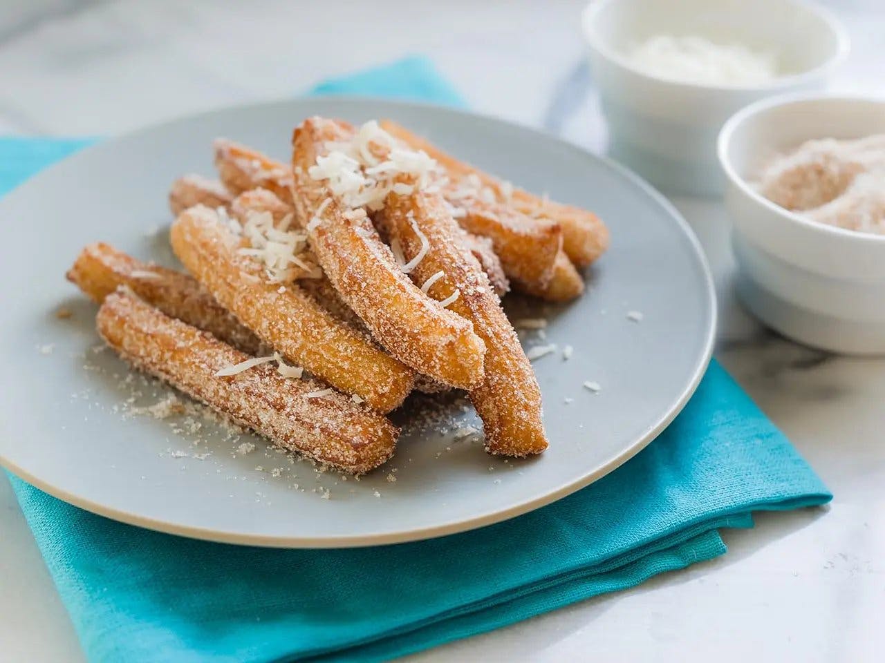 Close up of churros with cinnamon coconut sugar on plate.