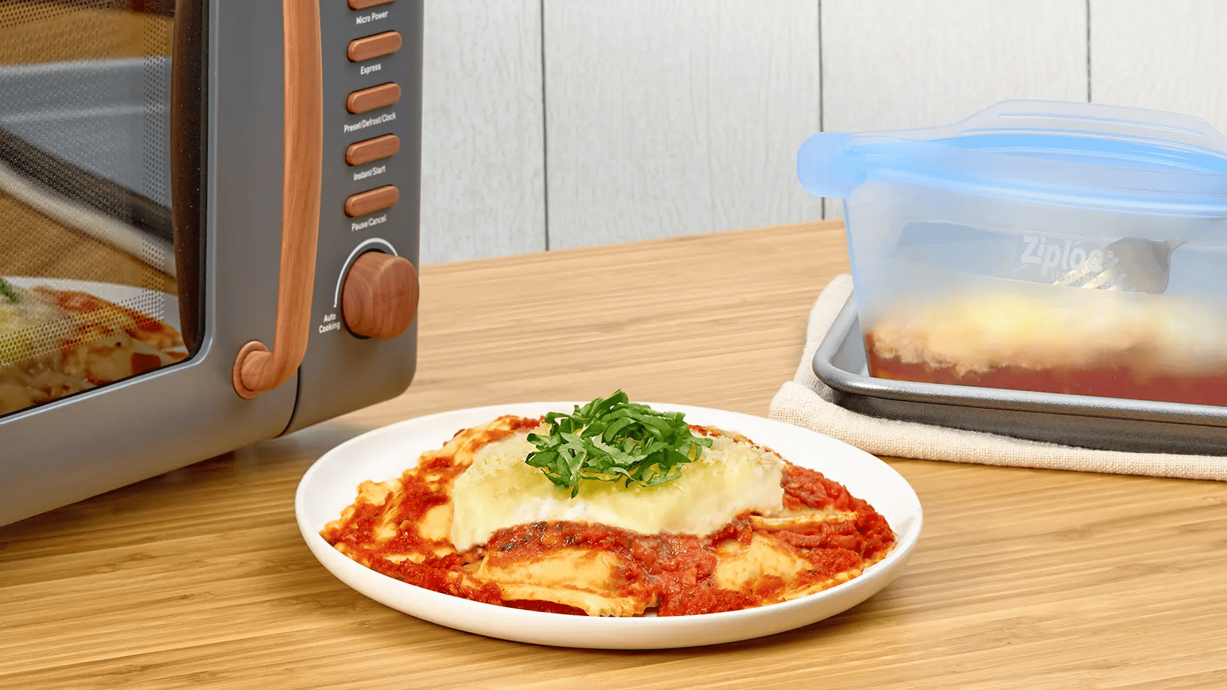 Lasagne au ravioli dans une assiette, à côté d’un contenant Ziploc devant un four à micro-ondes.